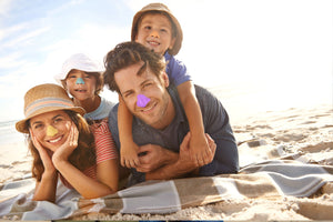 Family uses zinc oxide sunscreen to protect face at the beach.